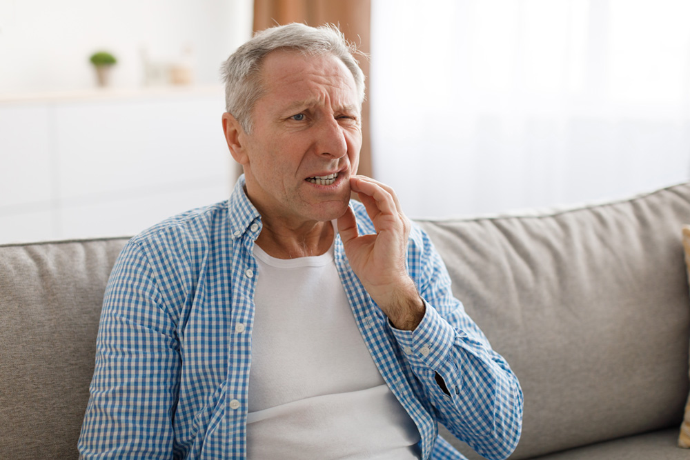 Older man suffering from mouth pain, showing the need for periodontal therapy