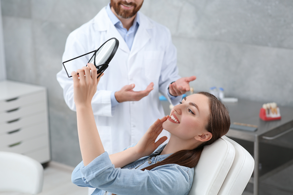 Woman at the dentist, admiring her new teeth