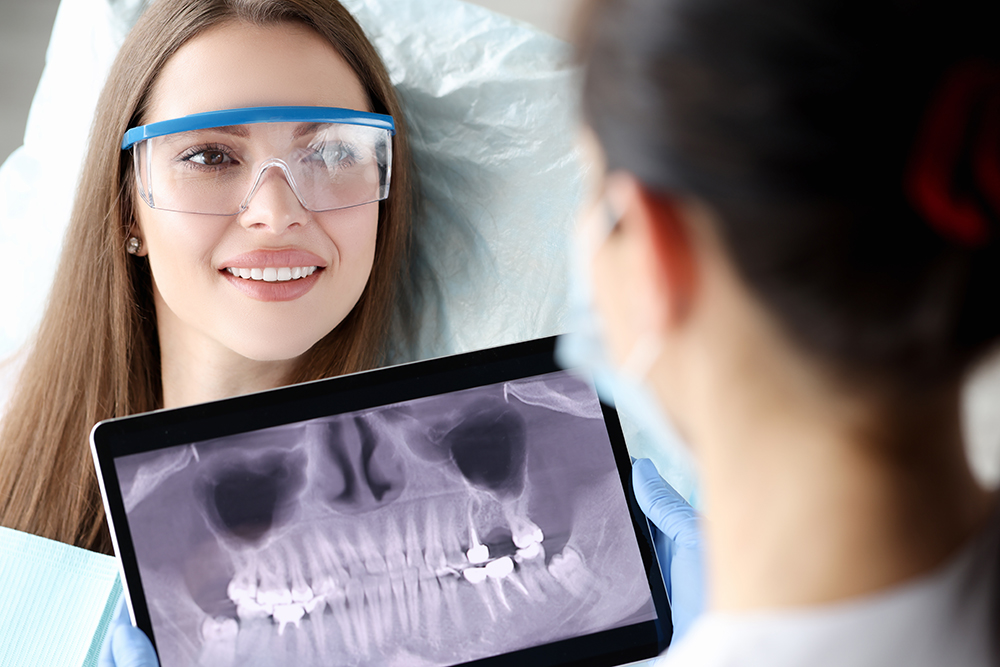 Dentist showing a female patient her dental X-ray as part of oral cancer screening