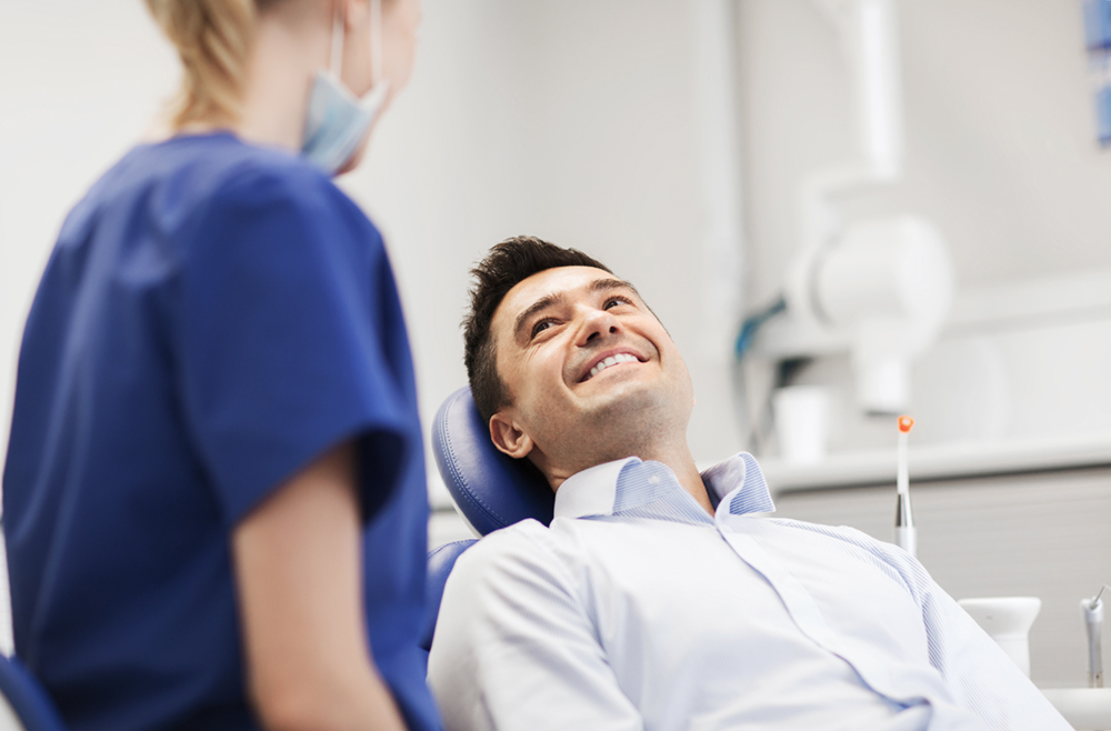 Man smiling at the dentist demonstrating the importance of smooth wisdom teeth extraction