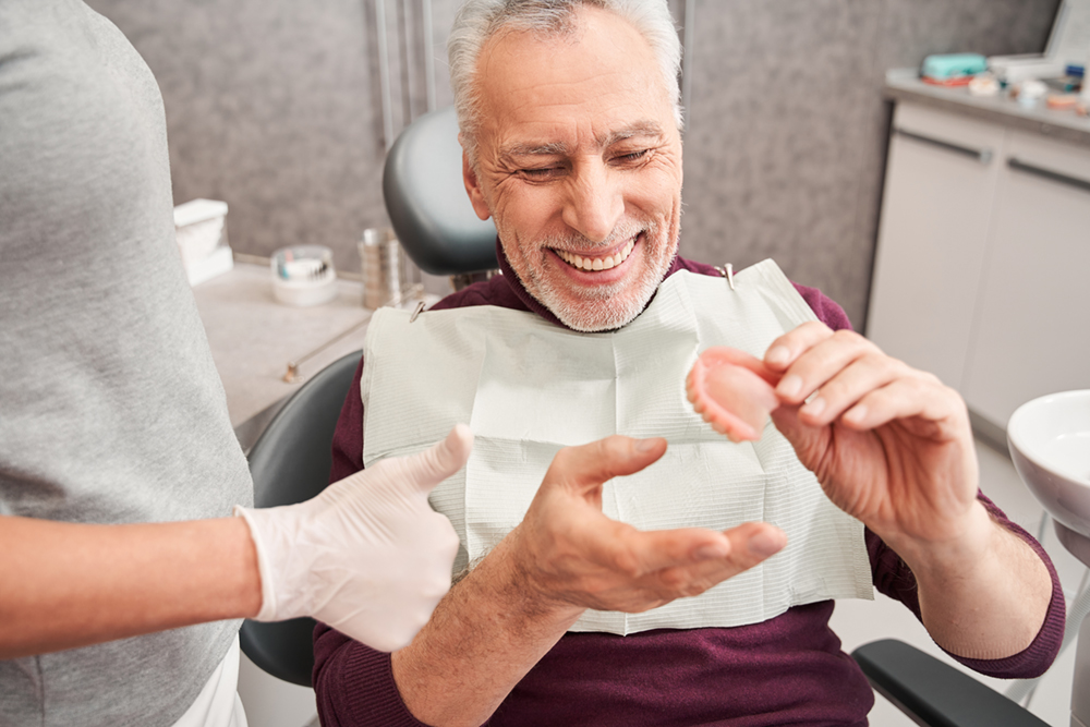 Older man receiving his dentures at the dentist